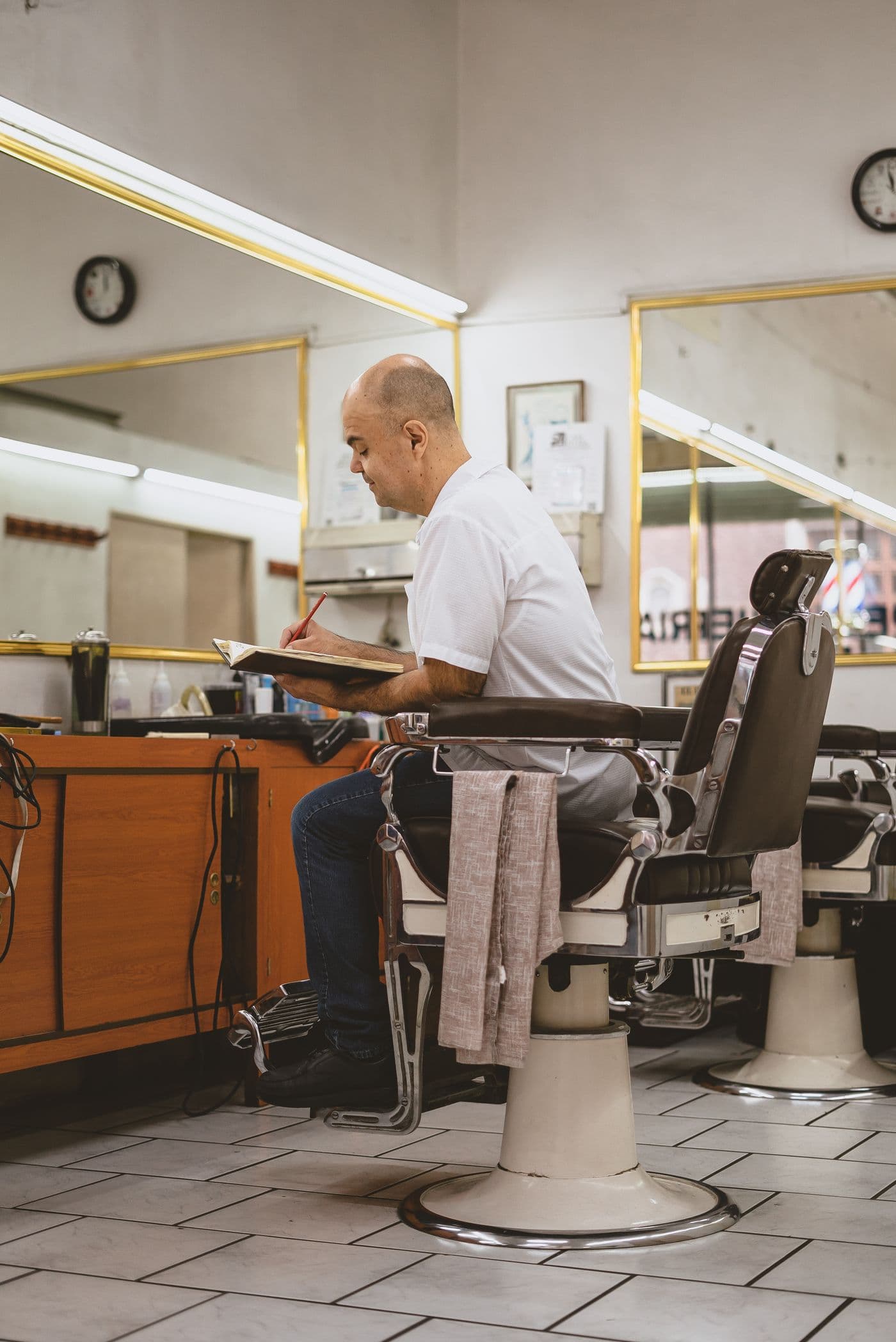 A barber writing up the day's takings in his shop