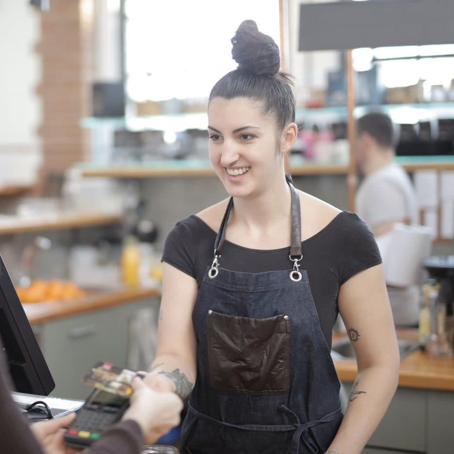 An owner taking a card payment across the counter of her cafe